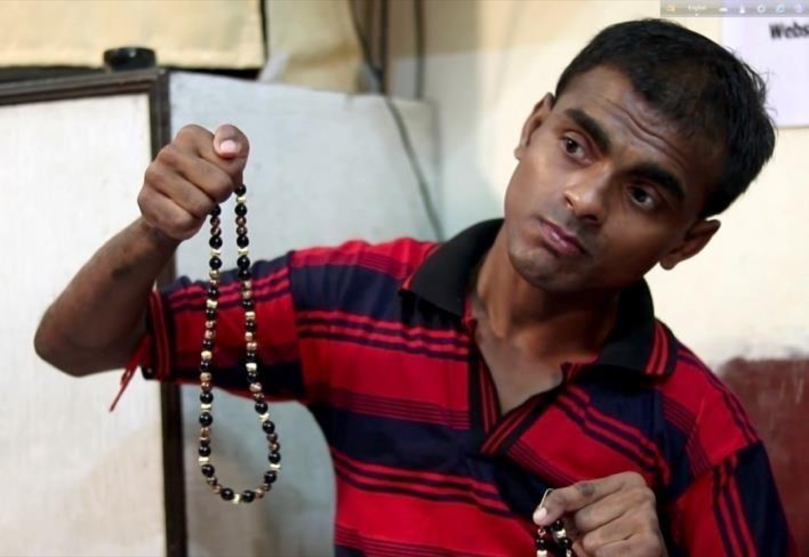 A trainee holds up a beaded necklace he made.