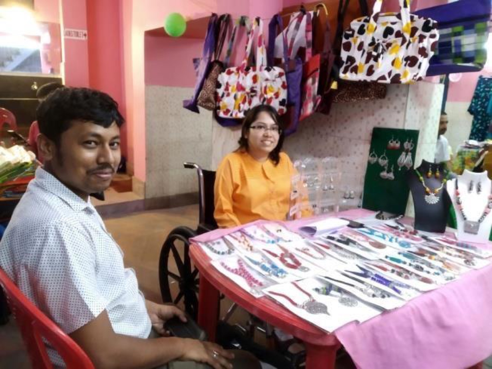 Two trainees at a DAND stall selling handmade jewellery and bags.